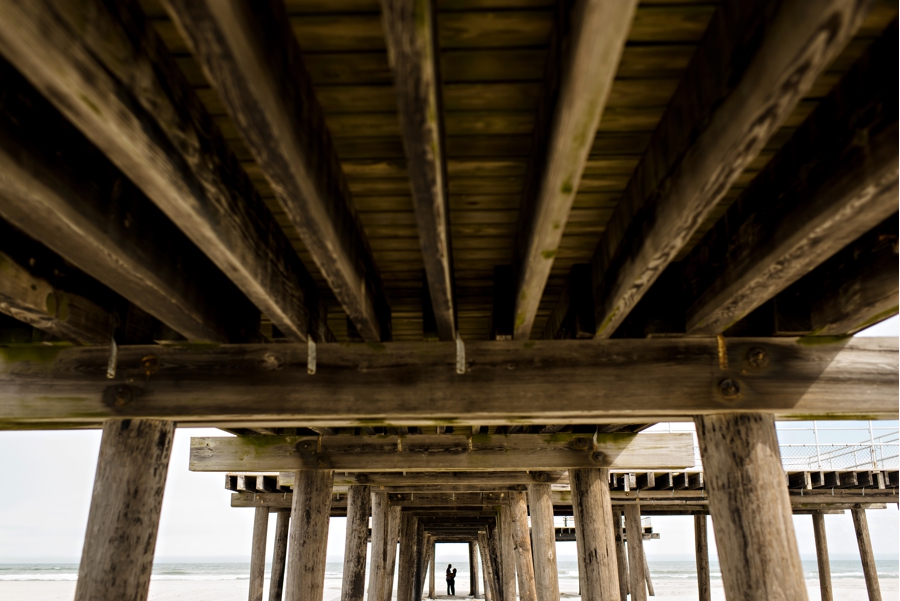 A silhouette of an engaged couple under the pier in cape may, nj.
